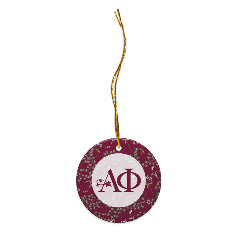 Alpha Phi Holiday Ornament shown with gold hanging cord and Alpha Phi logo and floral print