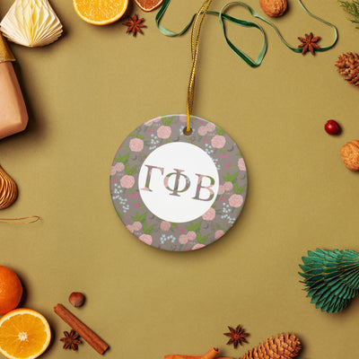 Gamma Phi Beta Ceramic Holiday Ornament shown in lifestyle setting with gold hanging thread with our filled letters and floral print trim in a la mode