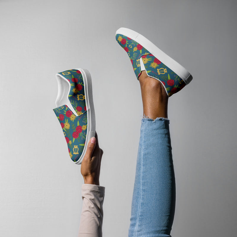 New! Alpha Chi Carnation Teal Floral Print Slip-on Canvas Shoes in playful pose