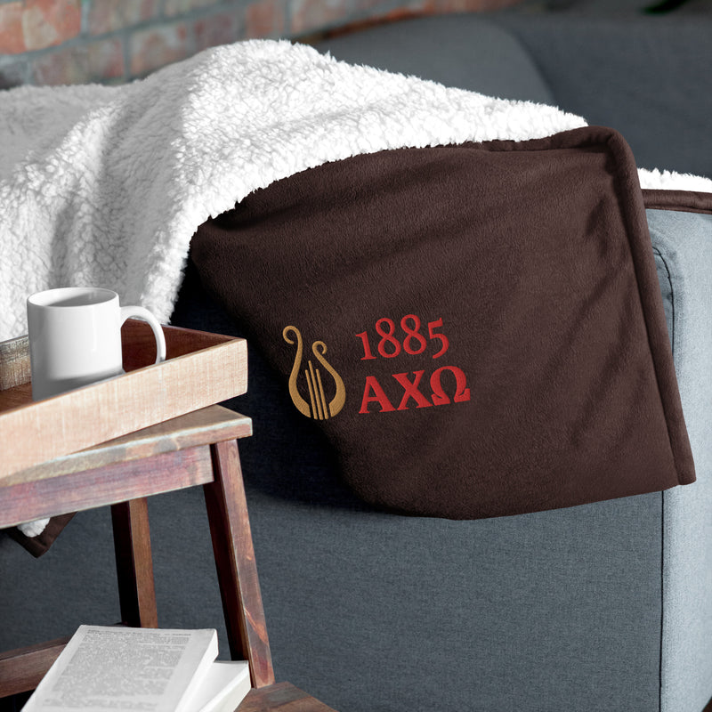 Alpha Chi Omega Plush Embroidered Sherpa Blanket in brown on chair