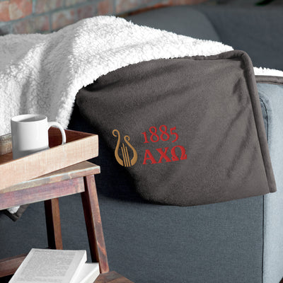 Alpha Chi Omega Plush Embroidered Sherpa Blanket in gray on chair