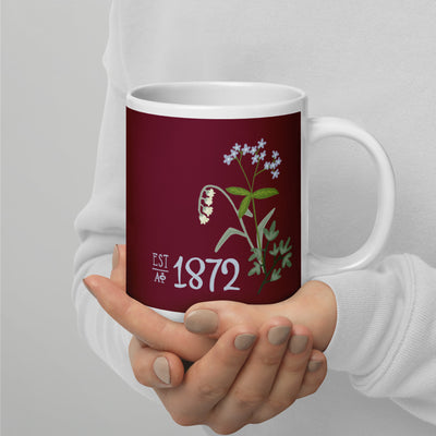 Alpha Phi 1872 Sorority Mug in 20 oz size shown in model's hands in Bordeaux color with Alpha Phi letters