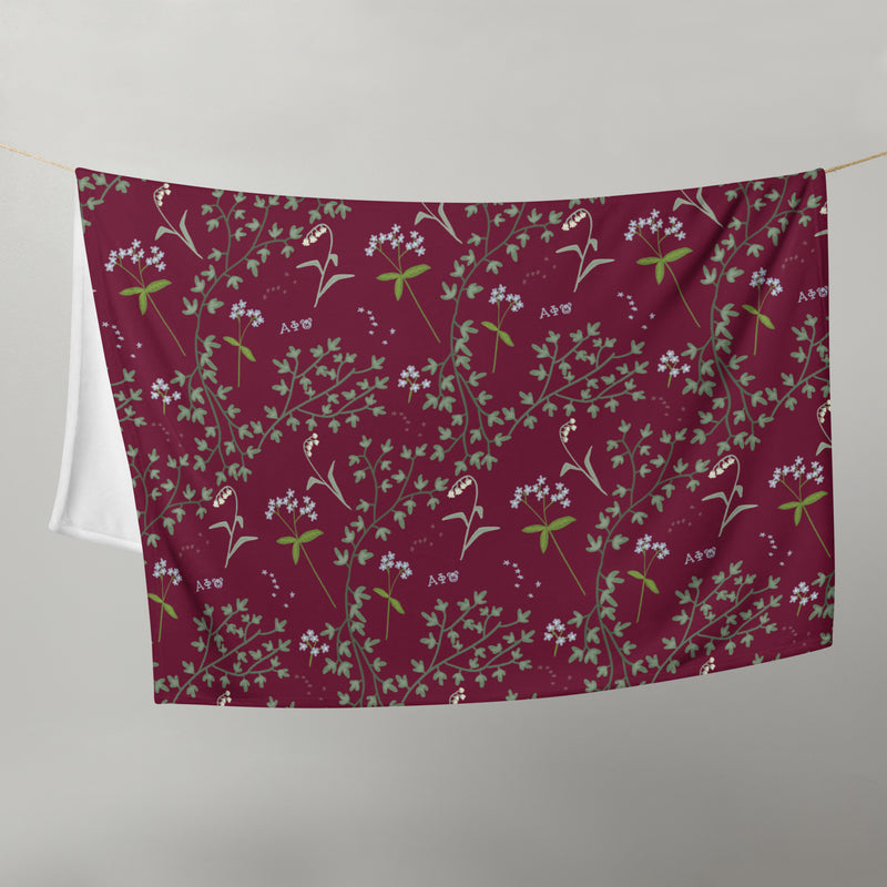 Alpha Phi Ivy and Lily Sorority Blanket in Bordeaux shown on clothesline with floral print