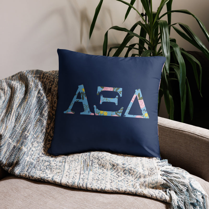 Alpha Xi Delta Sorority Pillow with Alpha Xi letters filled with floral print in 22" x 22" size shown on couch