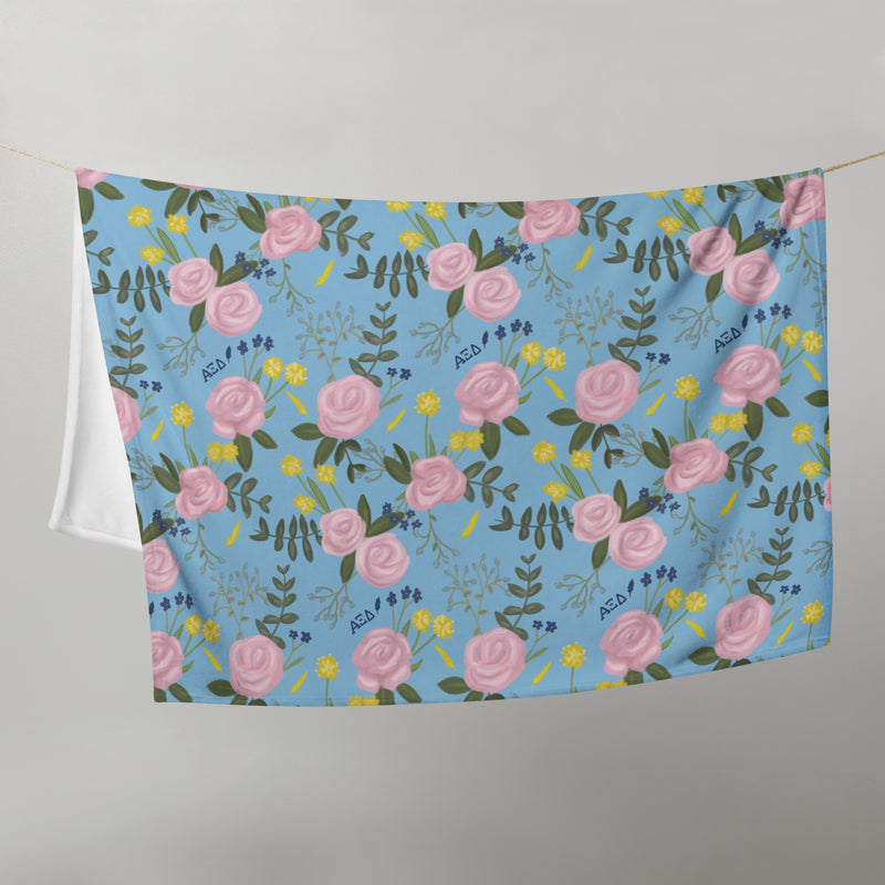 Alpha Xi Delta Sorority Blanket with rose floral print in light blue shown on clothesline