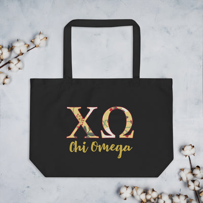 Chi Omega Letters Tote Bag in black shown with cotton blossoms