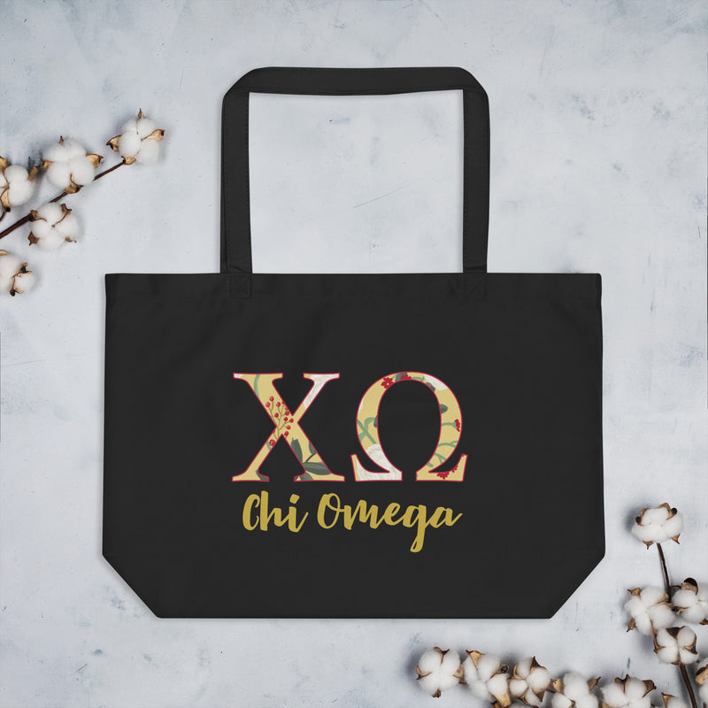Chi Omega Letters Tote Bag in black shown with cotton blossoms