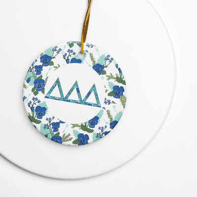 Delta Delta Delta Holiday ornament shown with gold hanging cord featuring filled Tri Delt letters and pansy floral print accent