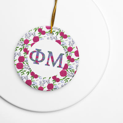 Phi Mu Holiday Ornament featuring filled Phi Mu letters and carnation floral print shown with gold hanging cord