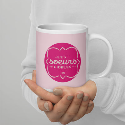 Phi Mu Motto Mug in 20 oz size shown in model's hands with handle on right