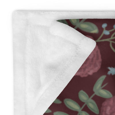 Pi Beta Phi floral print throw blanket in wine color shown in 50" x 60" size folded showing solid white reverse