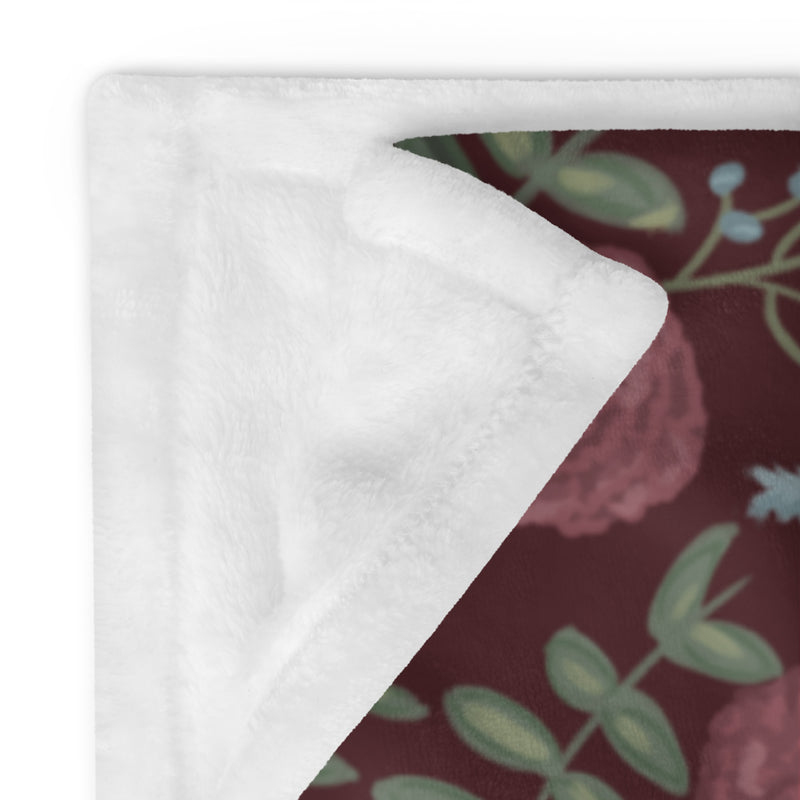 Pi Beta Phi floral print throw blanket in wine color shown in 50" x 60" size folded showing solid white reverse
