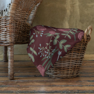 Pi Beta Phi floral print throw blanket in wine color shown wicker basket