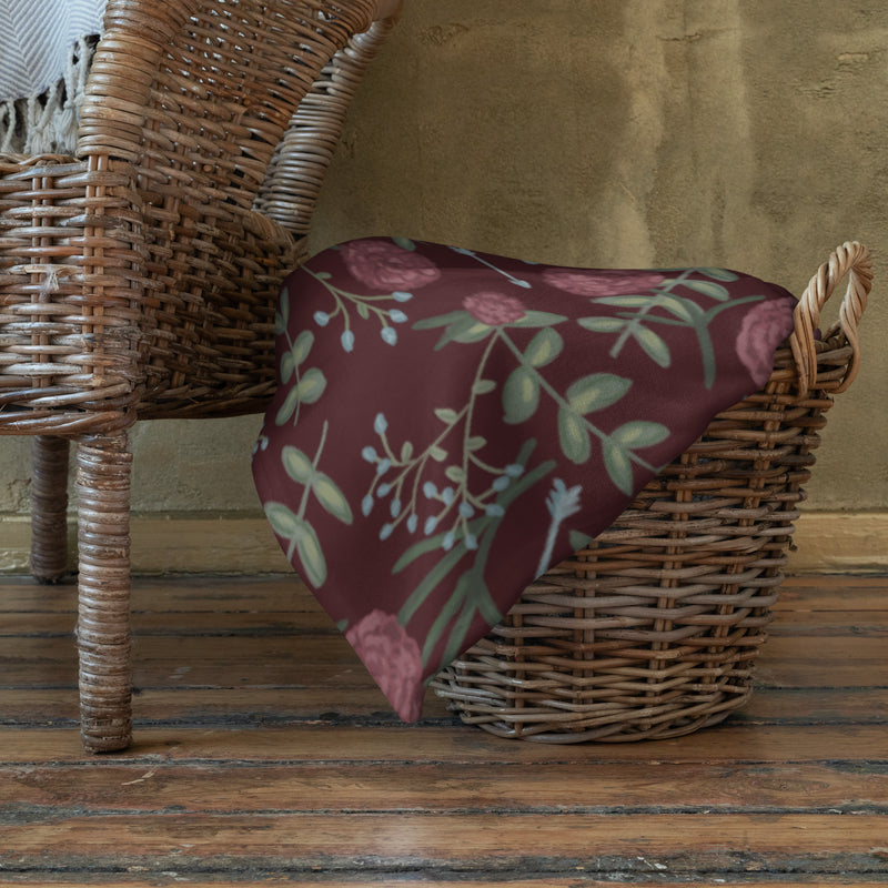 Pi Beta Phi floral print throw blanket in wine color shown wicker basket