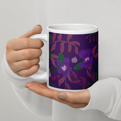 Sigma Kappa violet floral print mug shown in violet shown in model's hands in 20 oz size with handle on left