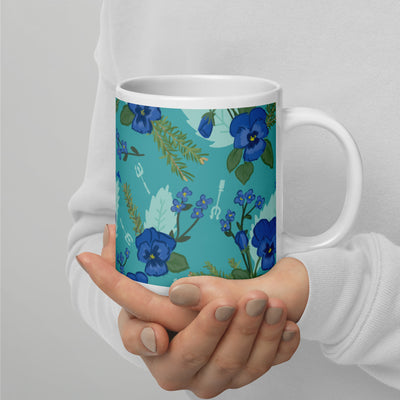 Tri Delta floral print mug in teal in larger 20 oz size shown in model's hands with handle on right