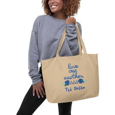 Tri Delta Sorority Tote Bag featuring Tri Delt motto and letters on natural oyster bag on model's arm