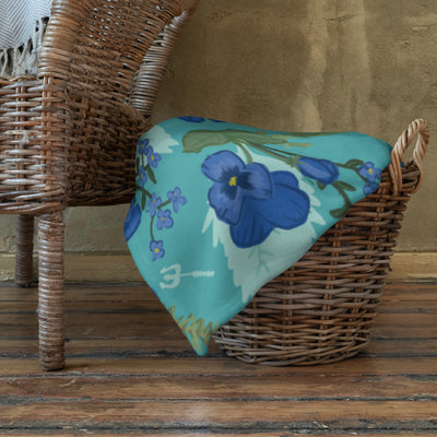 Tri Delta Sorority Throw Blanket shown in basket with pansy floral print in teal