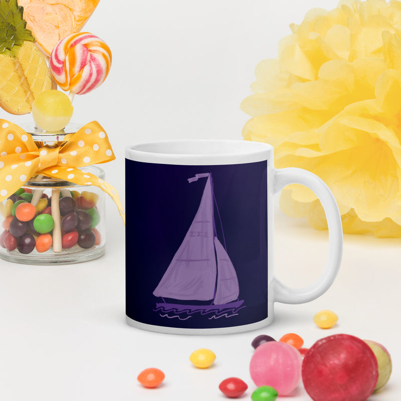 Tri Sigma sailboat mug in 11 oz size shown in colorful lifestyle setting with handle on right