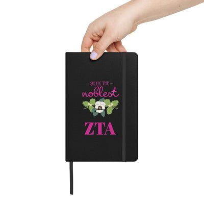 Zeta Seek the Noblest Motto Journal in black shown in woman's hand