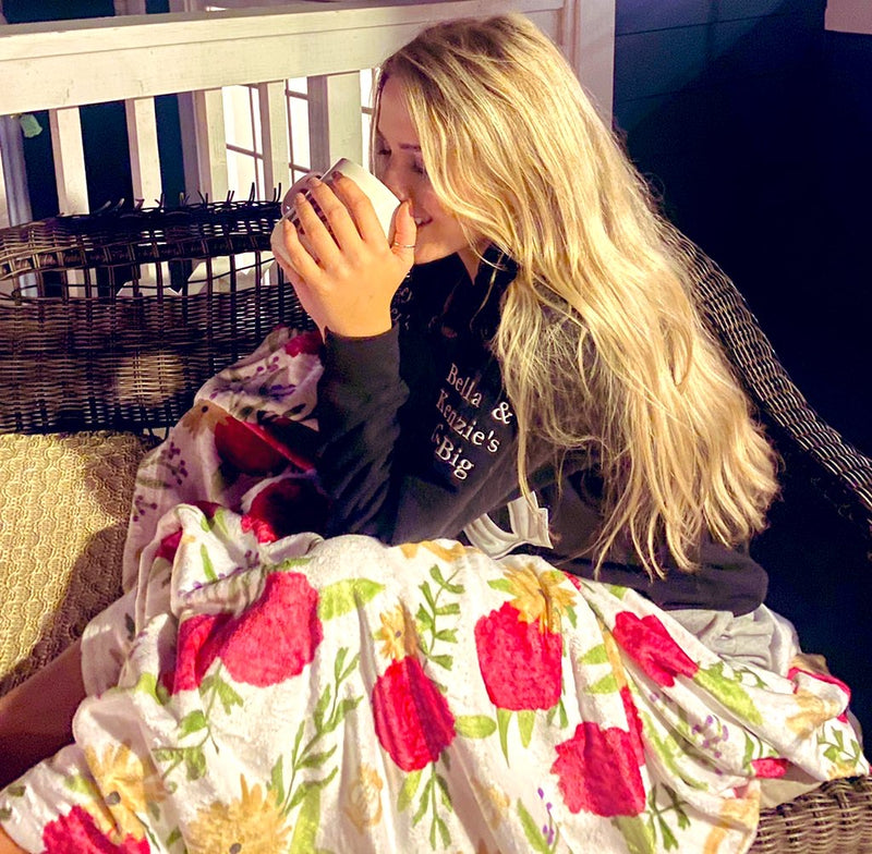 Alpha Chi Omega carnation floral print blanket in white lifestyle photo.