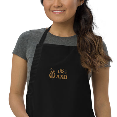 Alpha Chi Omega 1885 Lyre Embroidered Apron  in zoomed in view in black on young woman