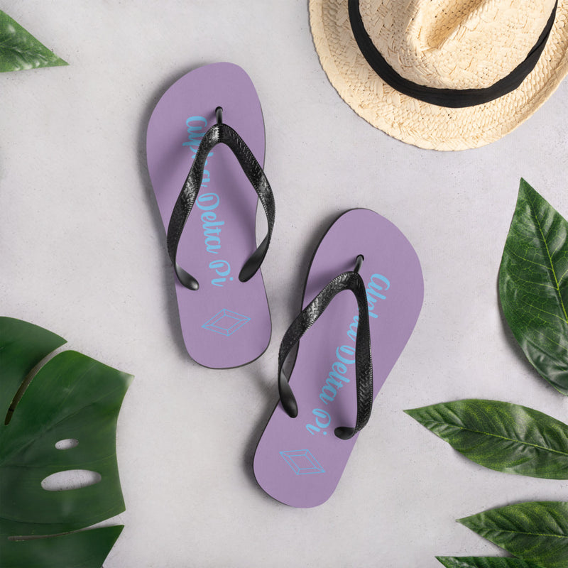 Alpha Delta Pi purple fliip flops with sorority name and Diamond symbol in lifestyle setting.