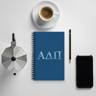 Alpha Delta Pi Greek Letters Spiral Notebook shown with coffee