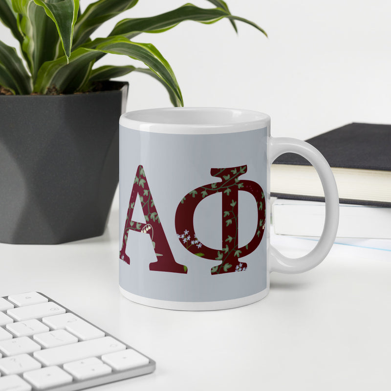 Alpha Phi Greek letters mug in Silver shown in office environment.