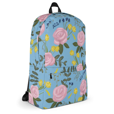 Alpha Xi Delta pink rose floral print backpack blue background showing side view and Greek letters..