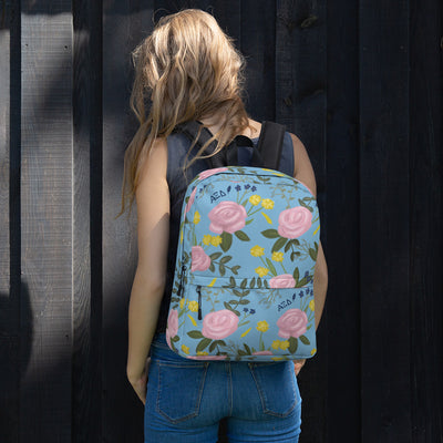 Alpha Xi Delta pink rose floral print backpack blue background shown on model's back