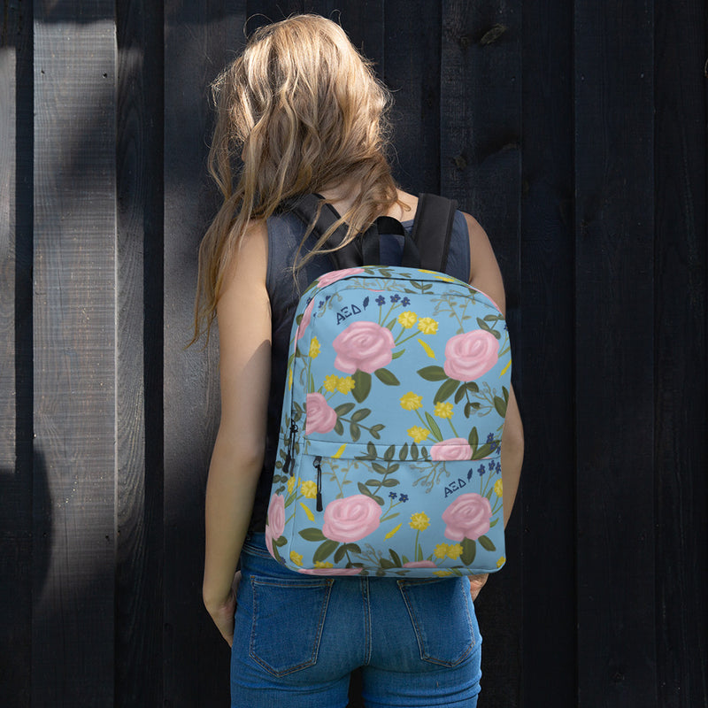 Alpha Xi Delta pink rose floral print backpack blue background shown on model&