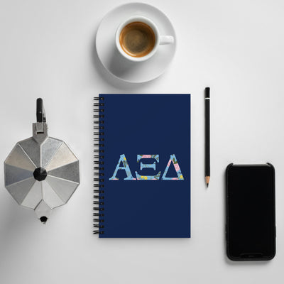 Alpha Xi Delta Greek Letters Spiral Notebook shown with coffee