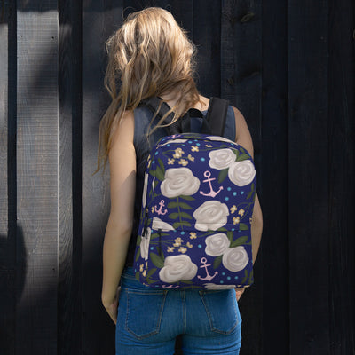 Delta Gamma white rose floral print backpack with a blue background shown on woman's back