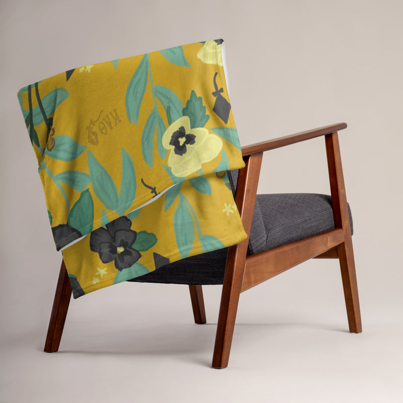 Kappa Alpha Theta Pansy Floral Print Blanket, Gold shown on chair