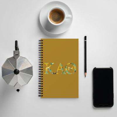 Kappa Alpha Theta Greek Letters Spiral Notebook shown with coffee