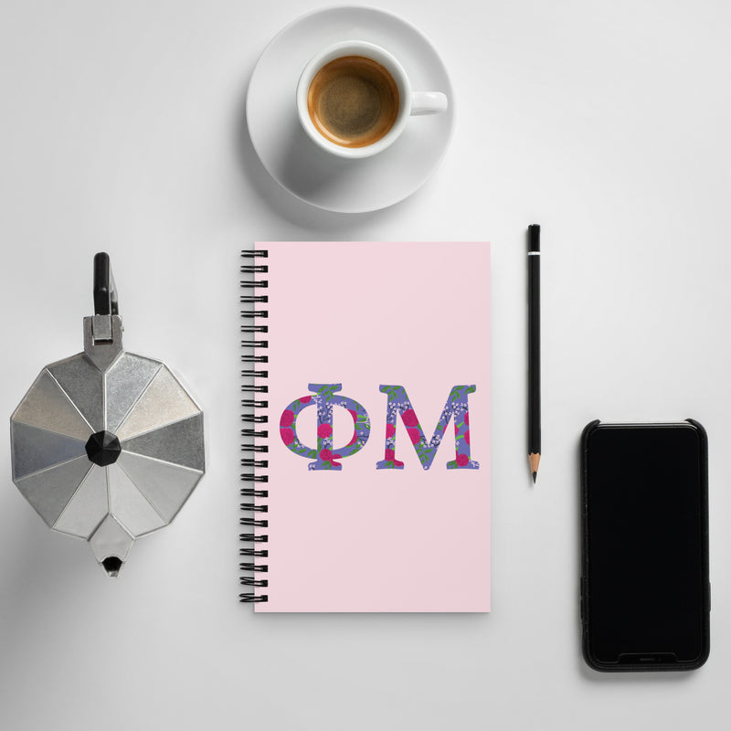 Phi Mu Letters Spiral Notebook shown with coffee in lifestyle setting