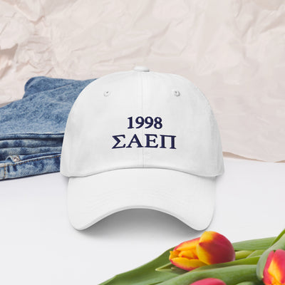 SAEPi embroidered baseball cap with SAEPi letters and founding year on white hat in lifestyle setting