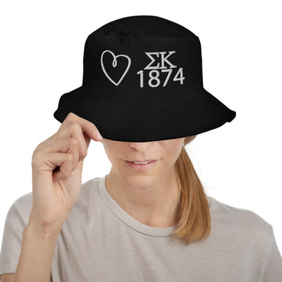 Sigma Kappa Heart Embroidered Bucket Hat in black shown with white embroidery on model's head