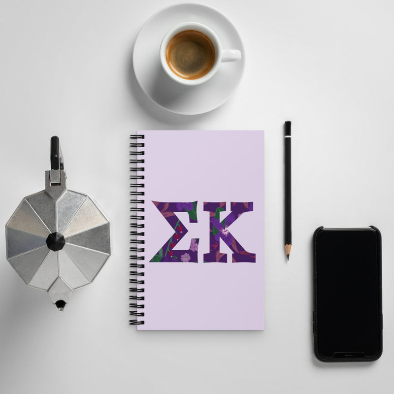 Sigma Kappa Filled Letters Spiral Notebook shown with coffee in lifestyle setting
