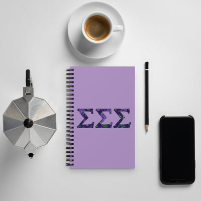 Tri Sigma Greek Letters Spiral Notebook shown with coffee