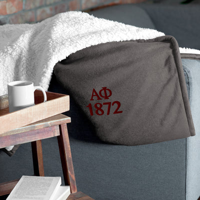 Alpha Phi Plush Embroidered Sherpa Blanket in gray on couch