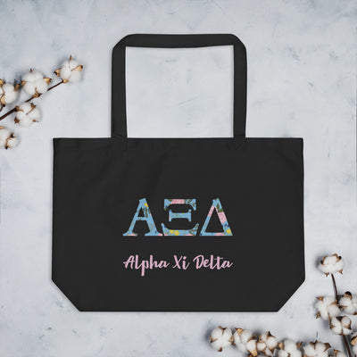 Alpha Xi Delta Letters Tote Bag in black shown flat with cotton blossoms