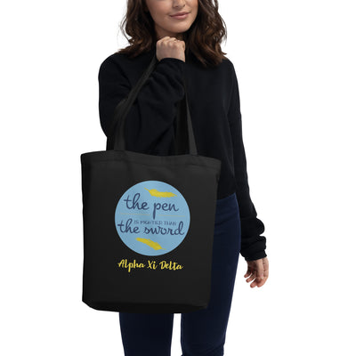 Alpha Xi Delta Pen is Mightier Eco Tote Bag in black shown on model's arm
