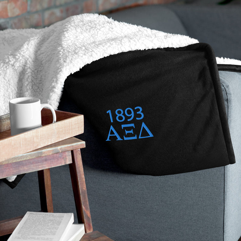 Alpha Xi Delta Plus Embroidered Sherpa Blanket in black on couch