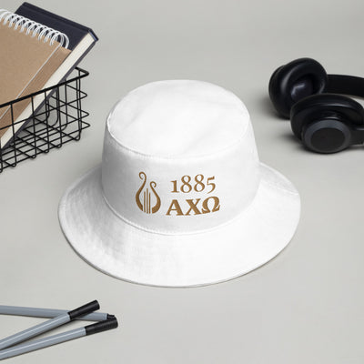 Alpha Chi Omega 1885 Greek Letters and Lyre Bucket Hat in white with gold shown in office