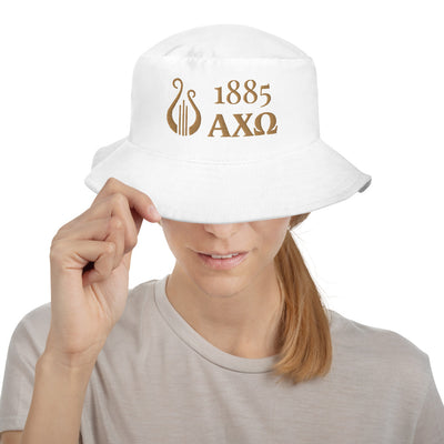 Alpha Chi Omega 1885 Greek Letters and Lyre Bucket Hat in white with gold embroidery shown on woman