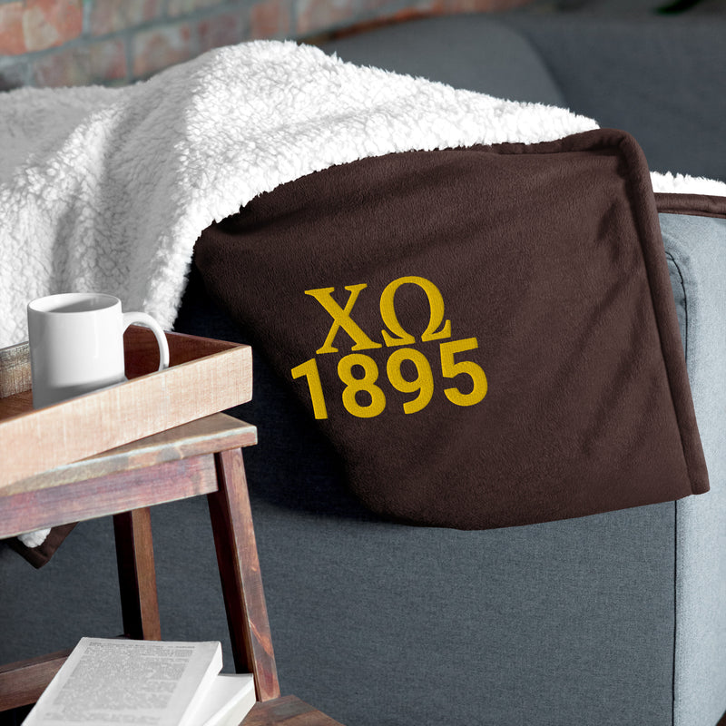 Chi Omega Plush Embroidered Sherpa Blanket in brown on couch