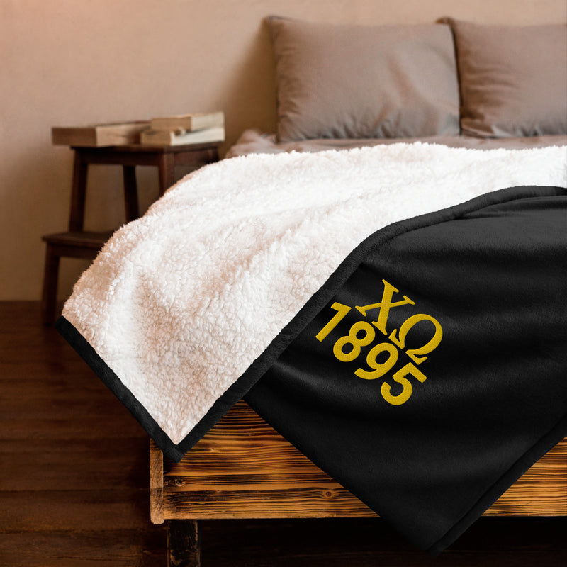 Chi Omega Plush Embroidered Sherpa Blanket in black on bed