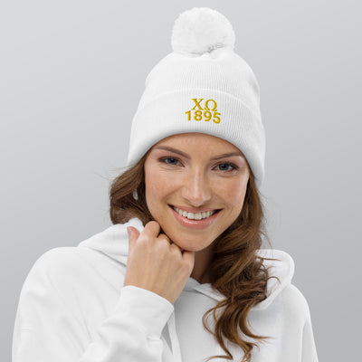 Chi Omega Pom Pom Beanie in white on model's head with gold embroidery